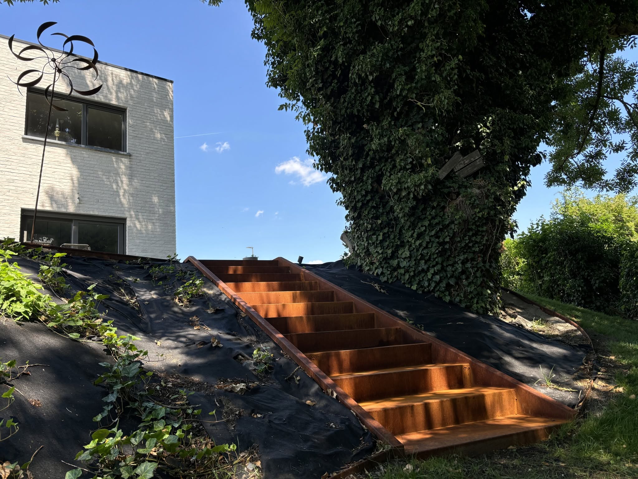 Escalier extérieur en acier Corten intégré à un terrain en pente